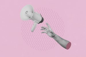 Hand catching a flying loudspeaker on a creative abstract pink background.
